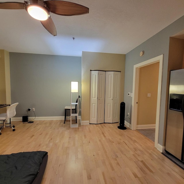 living area with baseboards, ceiling fan, and light wood finished floors