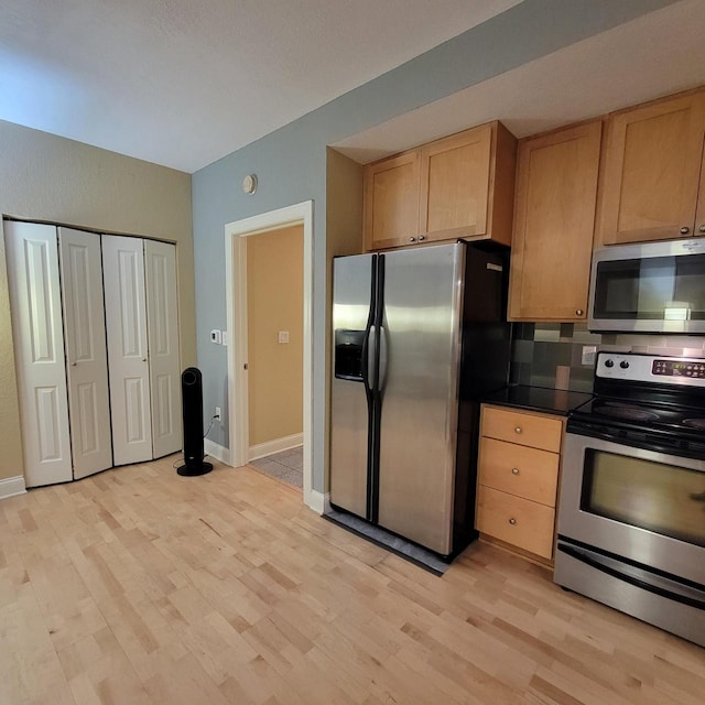 kitchen with light wood-style floors, light brown cabinets, appliances with stainless steel finishes, and baseboards