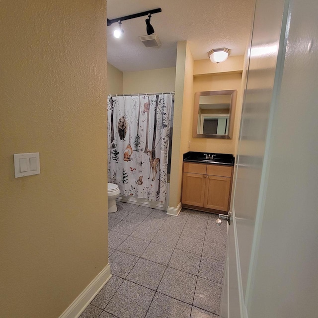 full bathroom with curtained shower, baseboards, toilet, vanity, and a textured ceiling