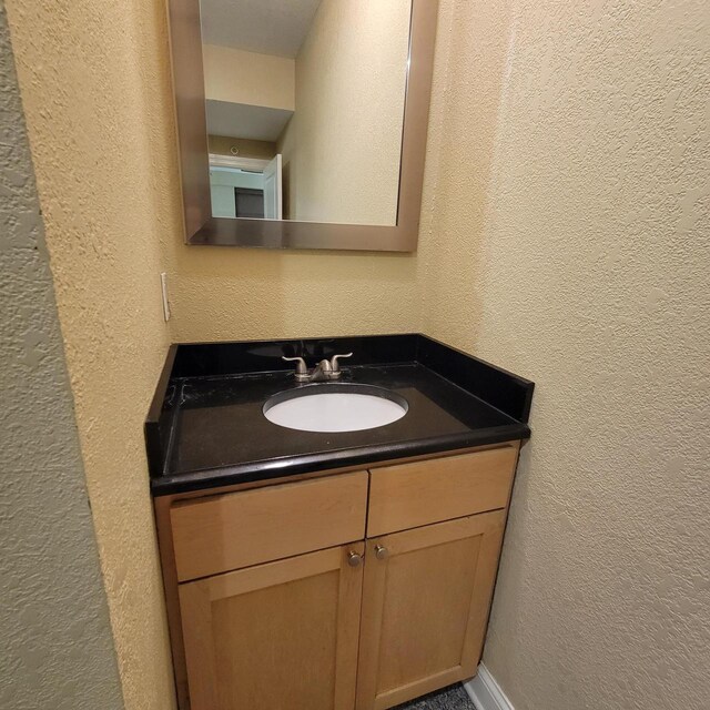 bathroom with vanity and a textured wall