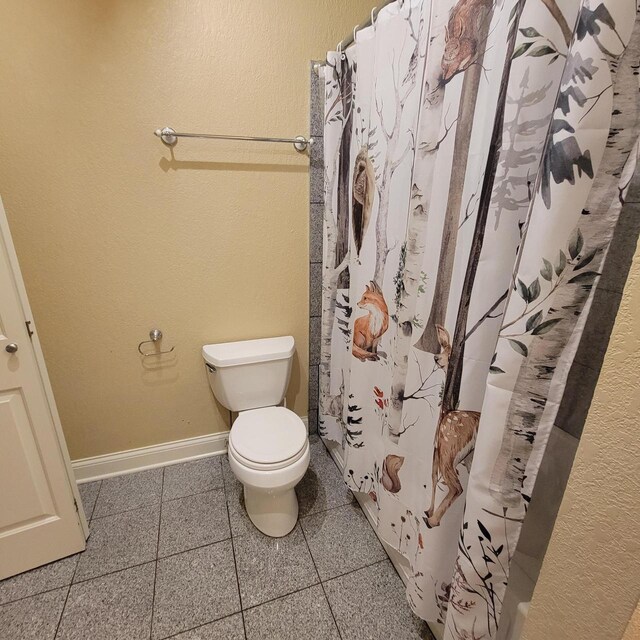 bathroom with tile patterned flooring, curtained shower, toilet, and baseboards