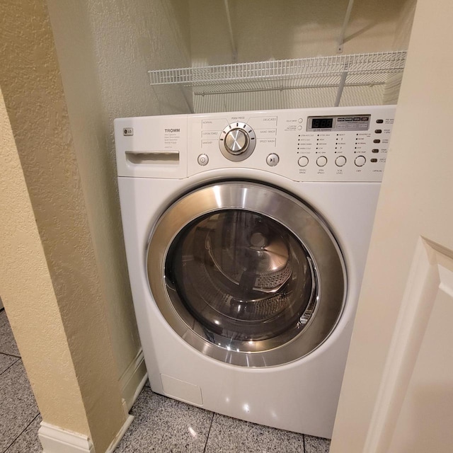 laundry room featuring washer / clothes dryer, a textured wall, and baseboards