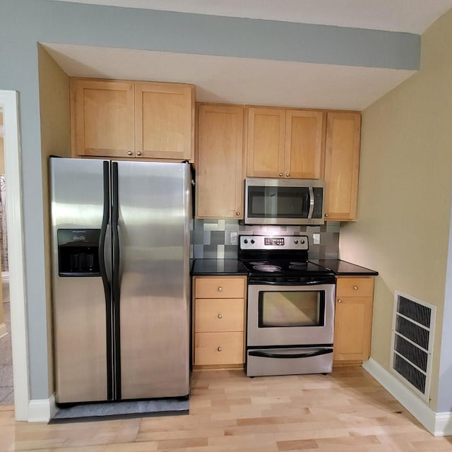 kitchen with dark countertops, visible vents, light brown cabinetry, and stainless steel appliances