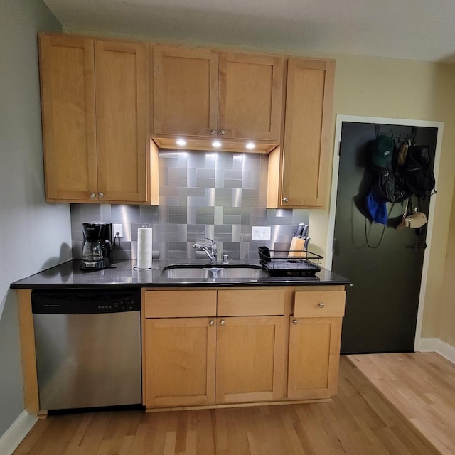 kitchen with dark countertops, dishwasher, decorative backsplash, light wood-style floors, and a sink