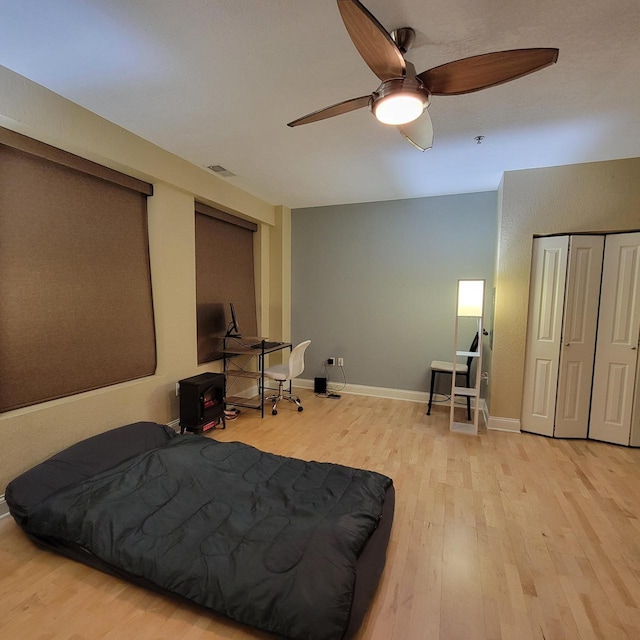 bedroom featuring ceiling fan, visible vents, baseboards, and wood finished floors