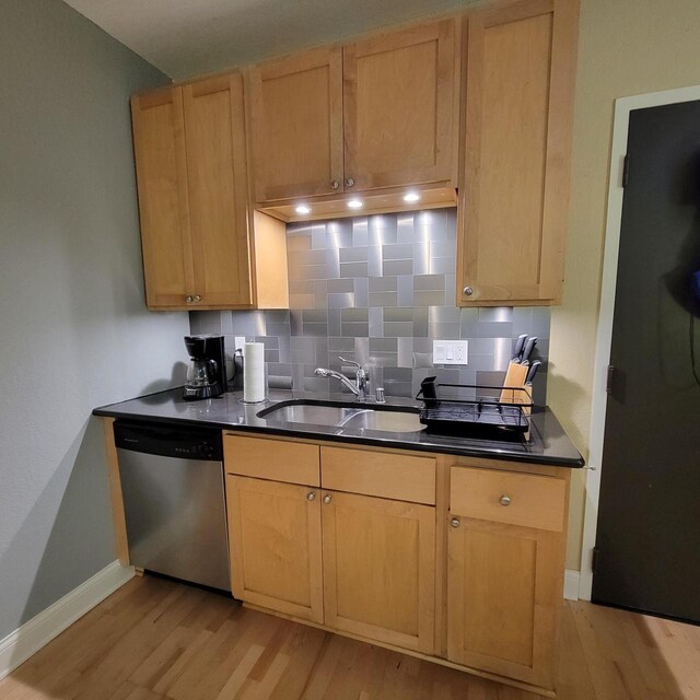 kitchen with light wood-type flooring, a sink, backsplash, dark countertops, and dishwasher