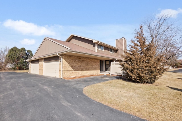 view of front facade with a chimney, a front lawn, a garage, aphalt driveway, and brick siding