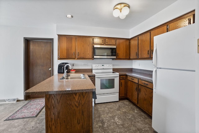 kitchen with visible vents, a sink, white appliances, a peninsula, and brown cabinetry