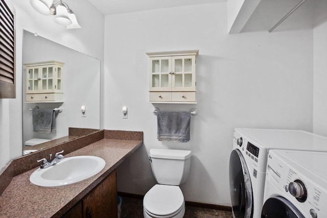 bathroom with washer and clothes dryer, toilet, vanity, and baseboards