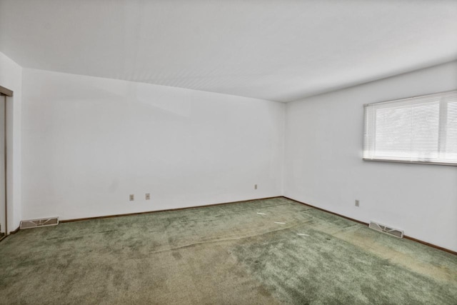 carpeted spare room with visible vents and baseboards