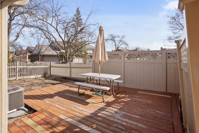 wooden terrace featuring central air condition unit, outdoor dining area, and a fenced backyard