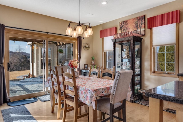 dining space with light wood finished floors and a notable chandelier