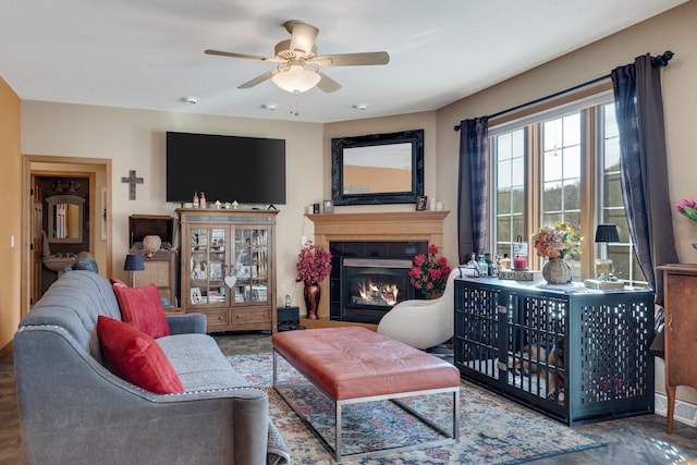 living area with a fireplace with flush hearth and ceiling fan