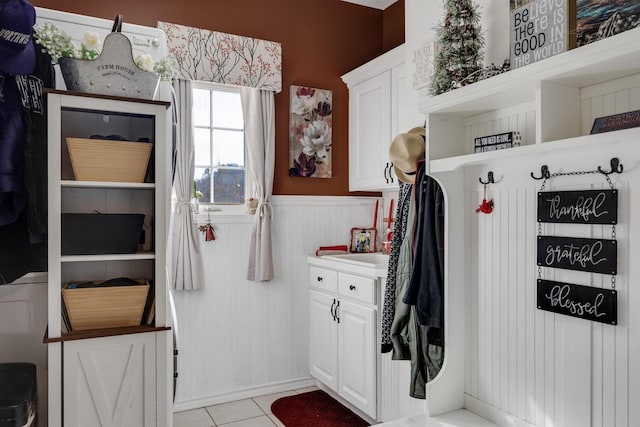 mudroom with light tile patterned floors and wainscoting