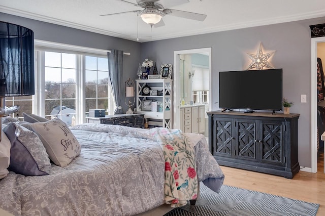 bedroom featuring a ceiling fan, crown molding, wood finished floors, and ensuite bath