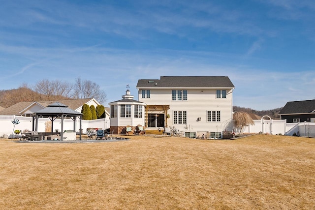 back of property with a gazebo, a patio, a lawn, and a fenced backyard