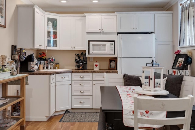 kitchen featuring white appliances, white cabinetry, glass insert cabinets, and light wood-style floors