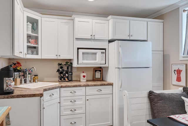 kitchen with a sink, white appliances, and white cabinetry