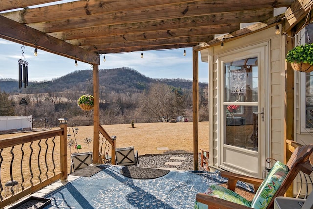 view of patio featuring fence, a mountain view, and a view of trees