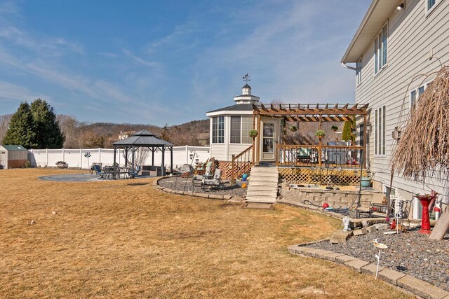 view of yard featuring a deck, a pergola, a patio, fence, and a gazebo