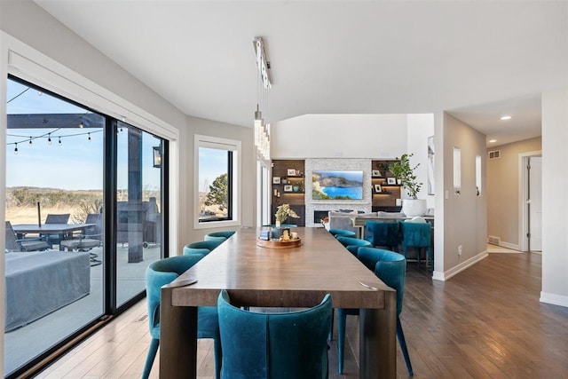 dining room featuring a large fireplace, plenty of natural light, and wood-type flooring