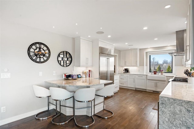 kitchen with a sink, tasteful backsplash, a peninsula, and built in fridge