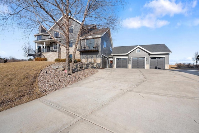 view of front of property featuring concrete driveway, a balcony, a garage, and stone siding