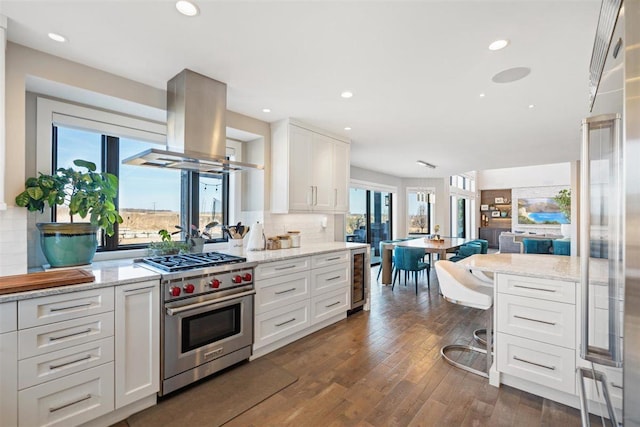 kitchen with dark wood finished floors, luxury stove, decorative backsplash, island range hood, and white cabinets