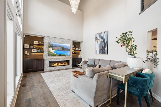 living area featuring visible vents, a fireplace, a towering ceiling, and hardwood / wood-style floors