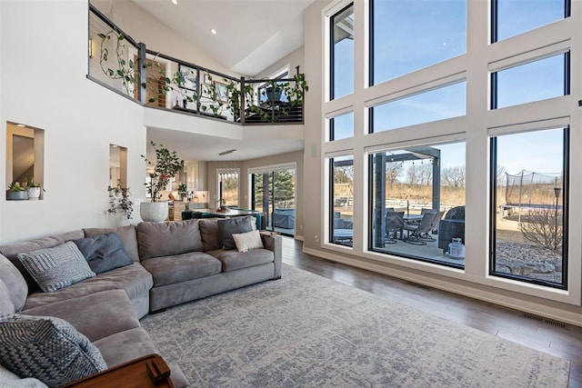 living area featuring visible vents, baseboards, lofted ceiling, and wood finished floors