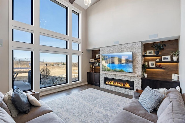 living room featuring visible vents, a fireplace, a high ceiling, and wood finished floors