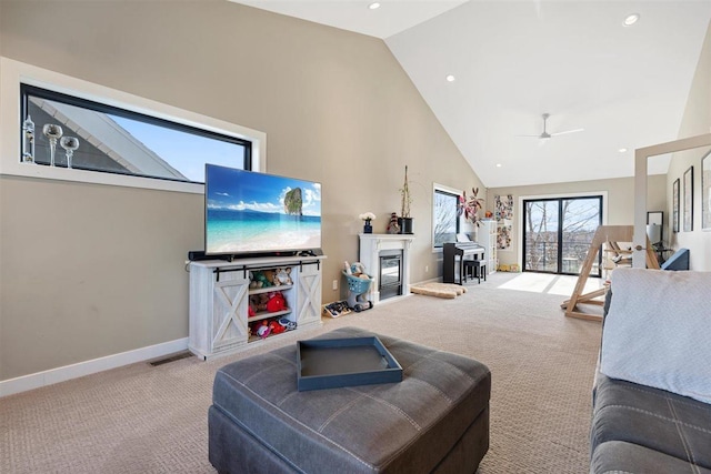 living area featuring a glass covered fireplace, carpet flooring, high vaulted ceiling, and baseboards