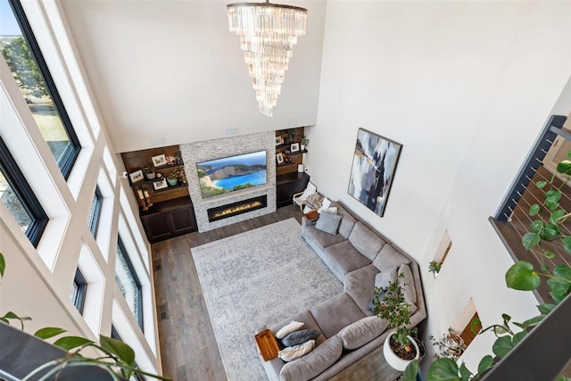 living room with a chandelier, a glass covered fireplace, and wood finished floors