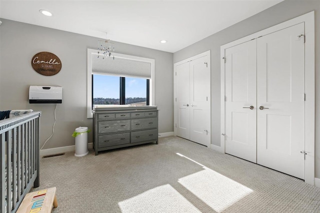 bedroom featuring visible vents, baseboards, two closets, and carpet floors