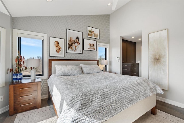 bedroom featuring baseboards, wood finished floors, and wallpapered walls