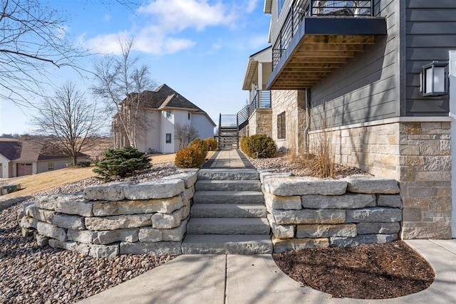 view of side of property featuring stone siding and stairs