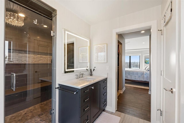 ensuite bathroom featuring connected bathroom, wood finished floors, a stall shower, and vanity