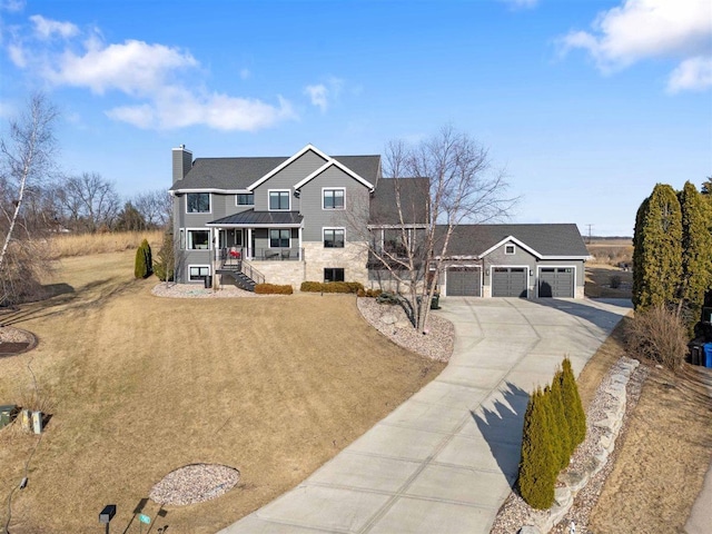 traditional-style home with a porch, a front yard, a chimney, a garage, and driveway