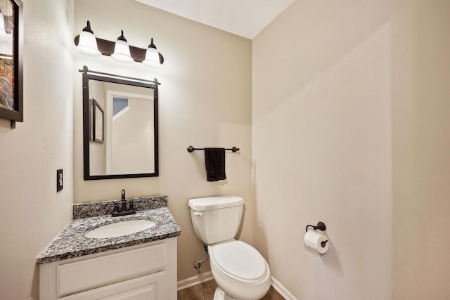 bathroom featuring toilet, vanity, baseboards, and wood finished floors