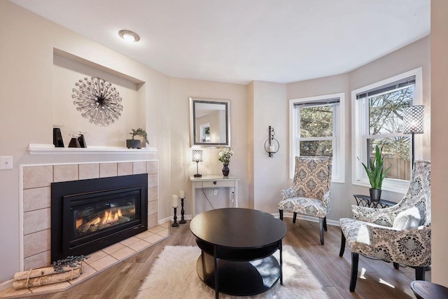 living area with a fireplace, baseboards, and wood finished floors