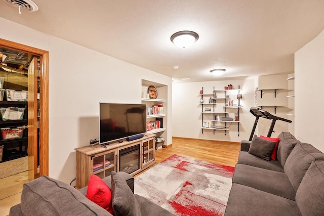 living room featuring visible vents, built in shelves, and wood finished floors