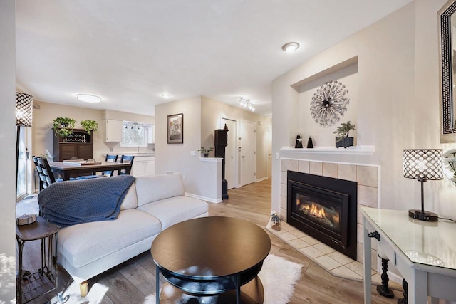 living room featuring light wood finished floors, a fireplace, and baseboards