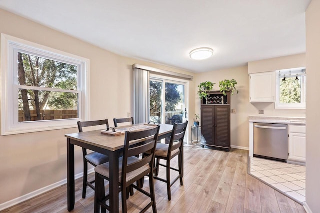 dining area with light wood finished floors, a healthy amount of sunlight, and baseboards