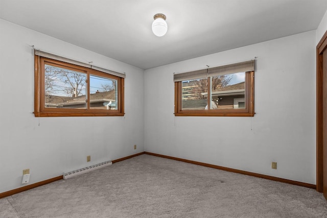 empty room featuring a baseboard radiator, baseboards, and carpet