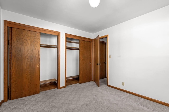 unfurnished bedroom featuring baseboards, carpet, and multiple closets