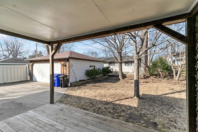 wooden terrace featuring an outbuilding, fence, and a garage