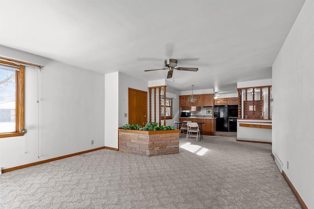 unfurnished living room with baseboards, light colored carpet, and a ceiling fan