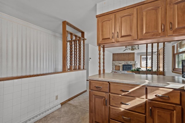 kitchen featuring light tile patterned floors, a fireplace, brown cabinets, and a baseboard radiator