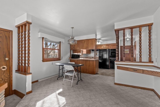 kitchen featuring brown cabinetry, baseboards, a baseboard radiator, a peninsula, and black appliances