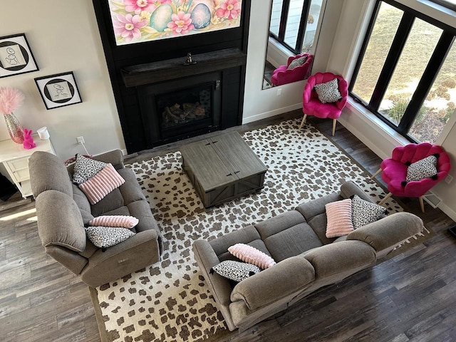 living area featuring a fireplace, baseboards, and wood finished floors